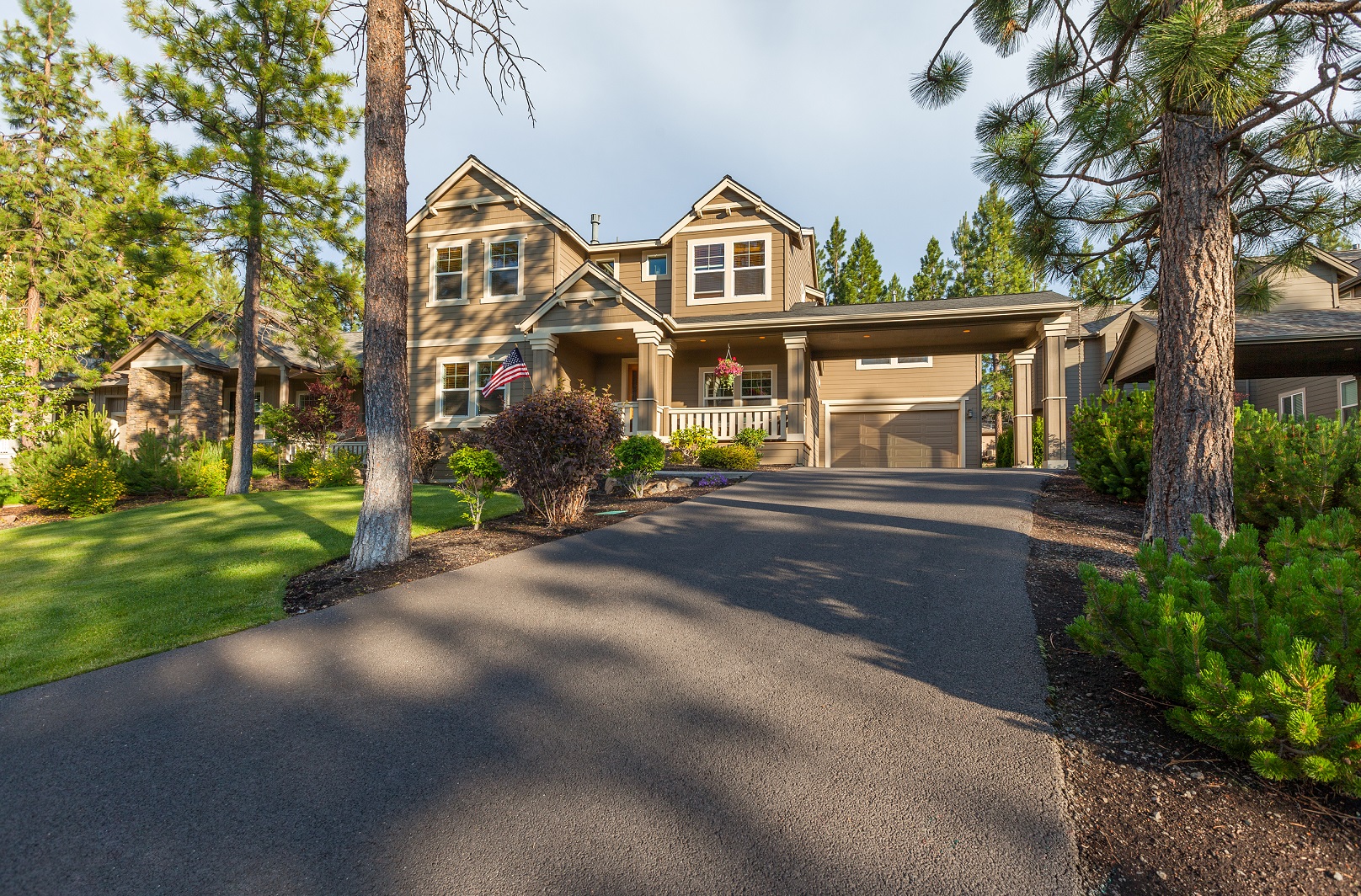 Beautiful Home Two-story house with a covered porch, green lawn, trees, and a wide paved driveway in front.