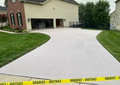 Freshly poured concrete driveway with caution tape blocking entry in front of a suburban house.