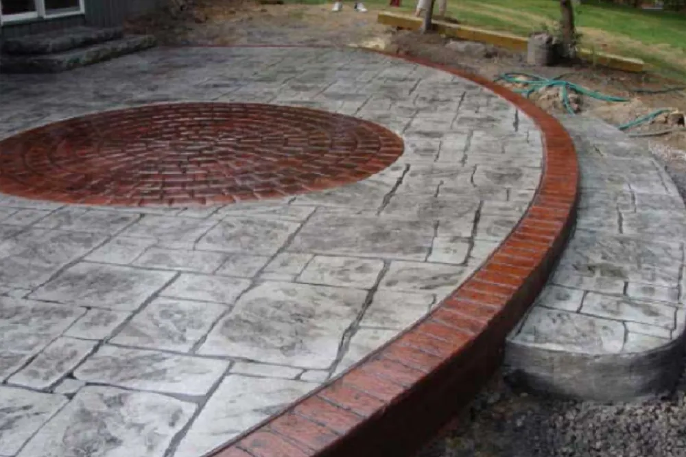 Circular brick patio with a central red brick design and a curved brick border on one side.