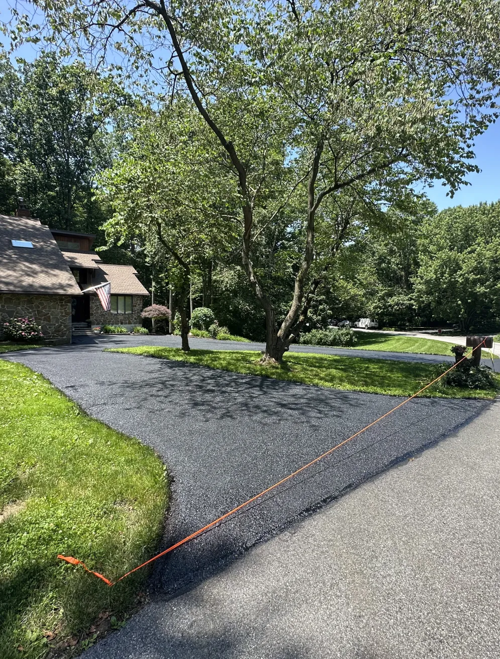 Freshly paved driveway with a tree in the center, orange caution tape blocks the entrance.