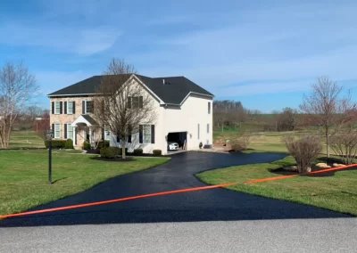 Two-story house with a curved driveway and an orange line across the driveway, set in a grassy yard.