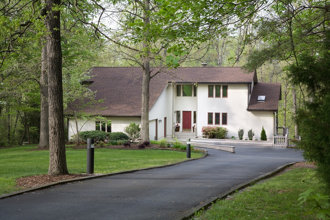 Modern Home Modern two-story house with brown roof, surrounded by trees, and a curved driveway in front.
