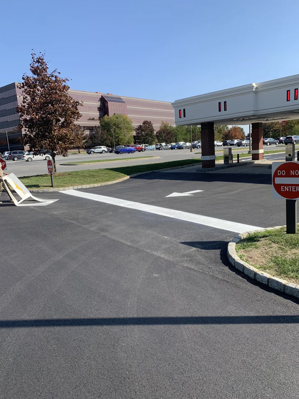 A drive-thru lane with "Do Not Enter" signs, an arrow, and an office building in the background.