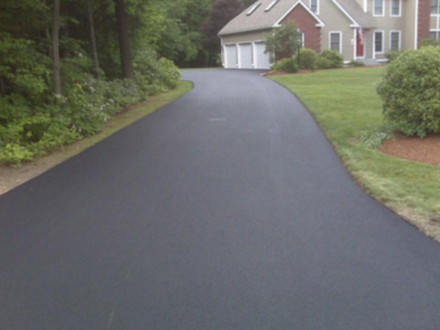 asphalt_residential_4_lrg Freshly paved asphalt driveway leading to a house with a garage, surrounded by green lawn and bushes.