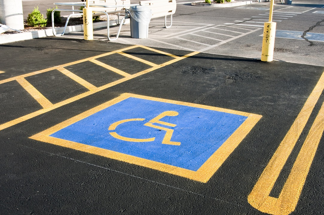 Blue and yellow empty handicap parking space Handicap parking space marked with a blue and white wheelchair symbol in a parking lot.